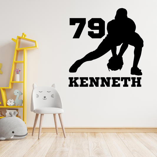 A black vinyl wall decal featuring a football player silhouette, the number 79, and the name KENNETH, displayed on a white wall in a child's bedroom setting next to a white cat chair and a yellow giraffe shelf.